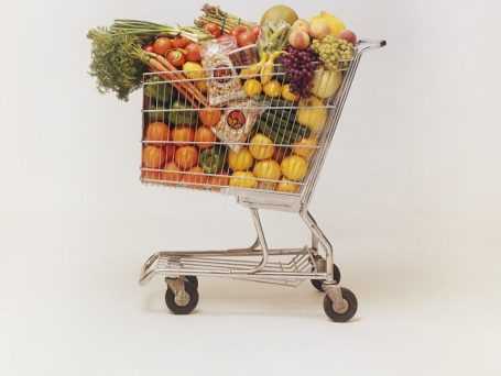 Chariot de courses rempli de fruits et légumes variés.